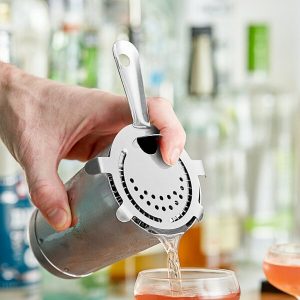Bartender using a Hawthorne strainer to pour the cocktail
