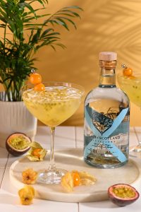 Passion Fruit Fizz cocktail with Heart of Scotland Original Gin, fresh passion fruit, ice and golden berry garnish beside the bottle.